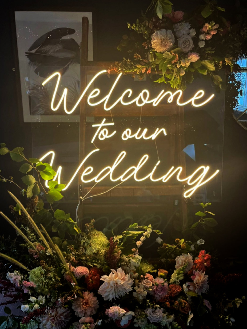 Letreiro neon 'Welcome to our wedding' na entrada do espaço